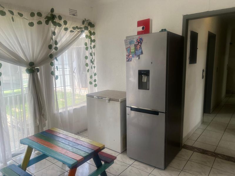 A functional kitchen area featuring tiled flooring and a sliding door providing access to the exterior.