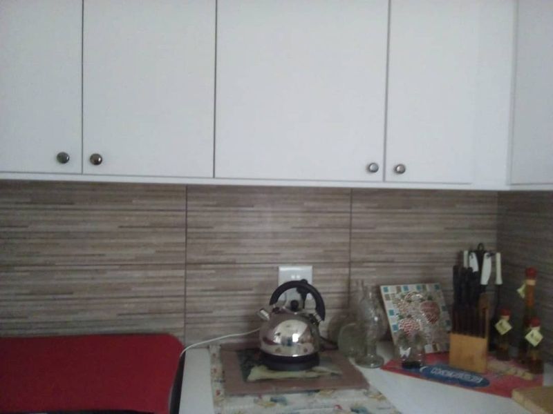 A kitchen area featuring white upper cabinetry and a horizontal tiled backsplash.