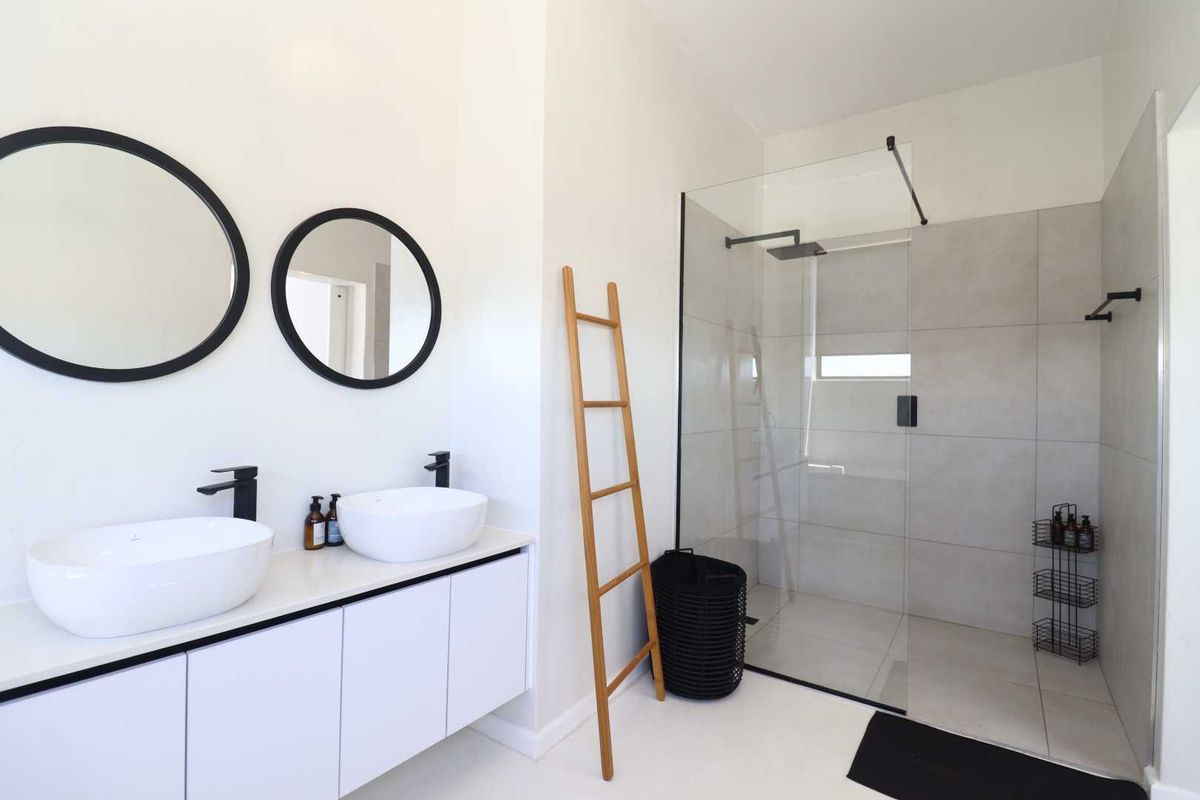 Modern bathroom featuring a double vanity with vessel sinks, matte black fixtures, and a spacious walk-in shower with a glass enclosure.