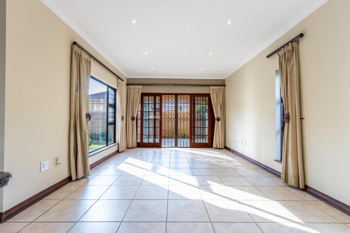 Spacious living area featuring tiled flooring, recessed downlighting, and large glass sliding doors providing access to the outdoor patio area.