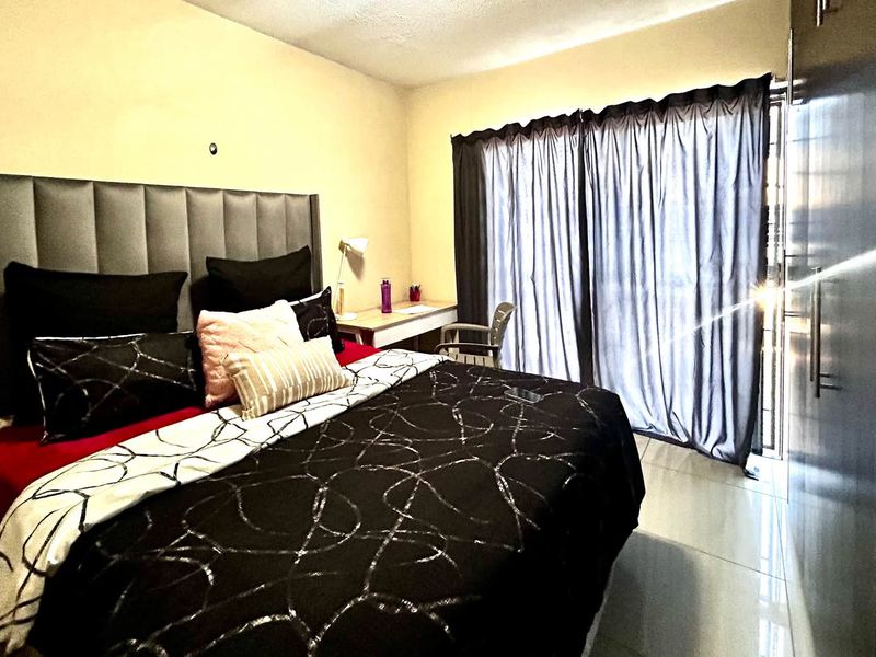 A well-lit bedroom featuring tiled flooring, a built-in wardrobe, and a sliding glass door providing access to the exterior.