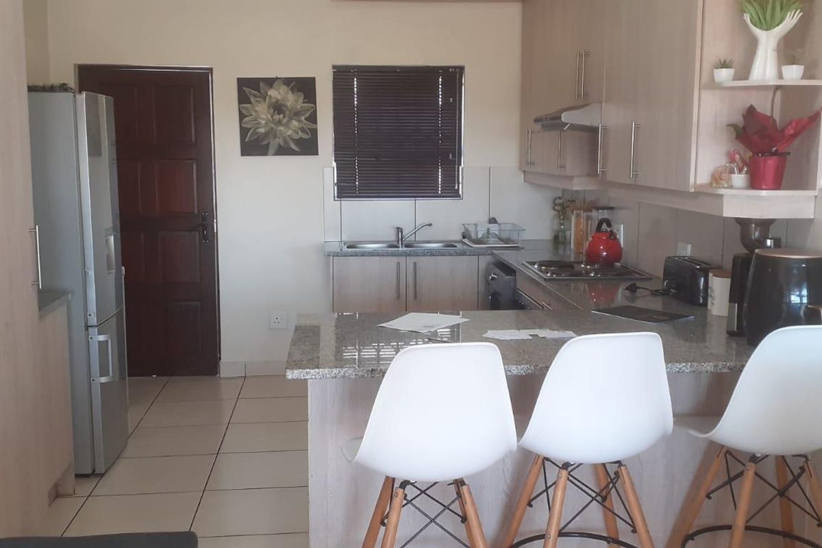 A functional kitchen featuring light wood cabinetry, granite countertops, a breakfast bar, and tiled flooring, providing a practical layout for daily use.