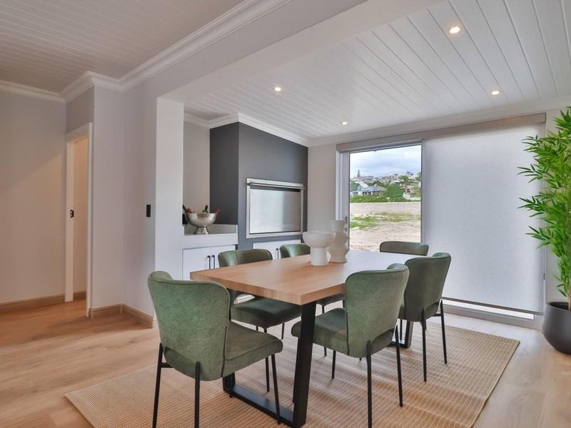 Modern dining area featuring timber flooring, a tongue and groove ceiling, and a built-in fireplace with direct access to the outdoor area.