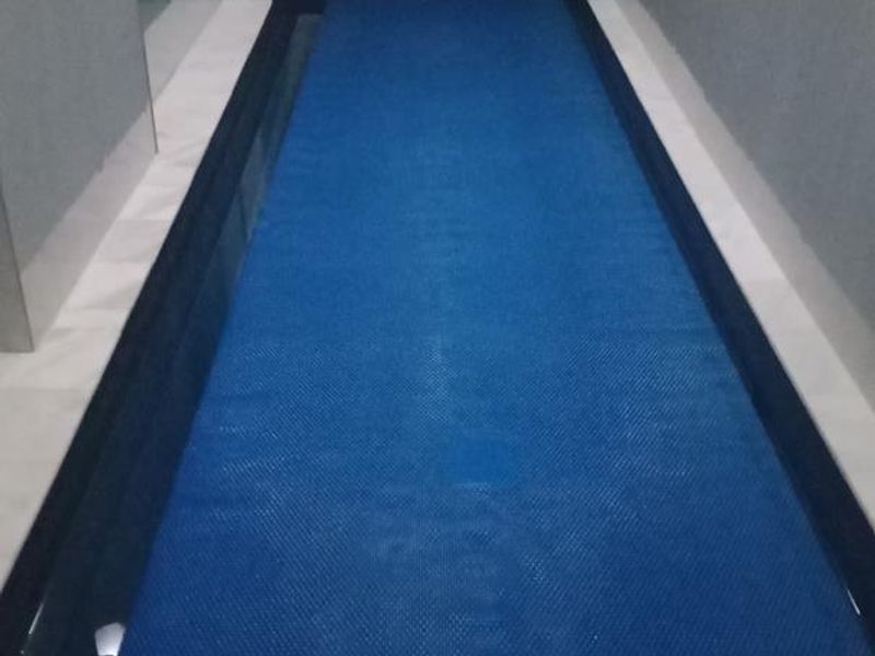 An indoor lap pool featuring modern tiled wall finishes and a protective pool cover.