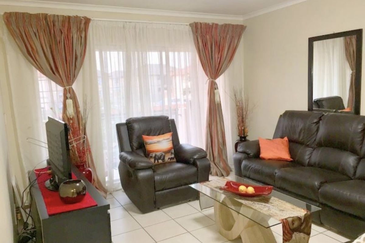 A comfortable living room featuring tiled flooring and a large sliding glass door that provides natural light and access to the exterior.