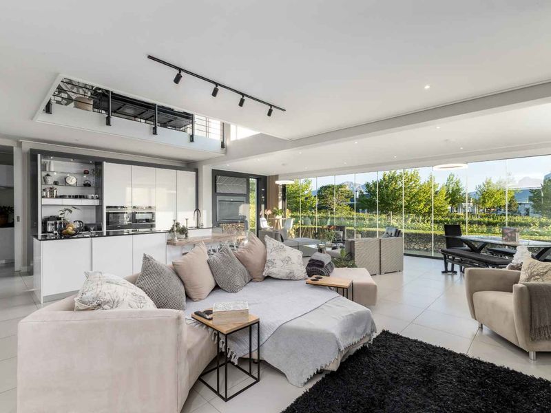 Spacious open-plan living area featuring a modern kitchen with integrated appliances, sleek cabinetry, and expansive floor-to-ceiling glass doors overlooking the garden.