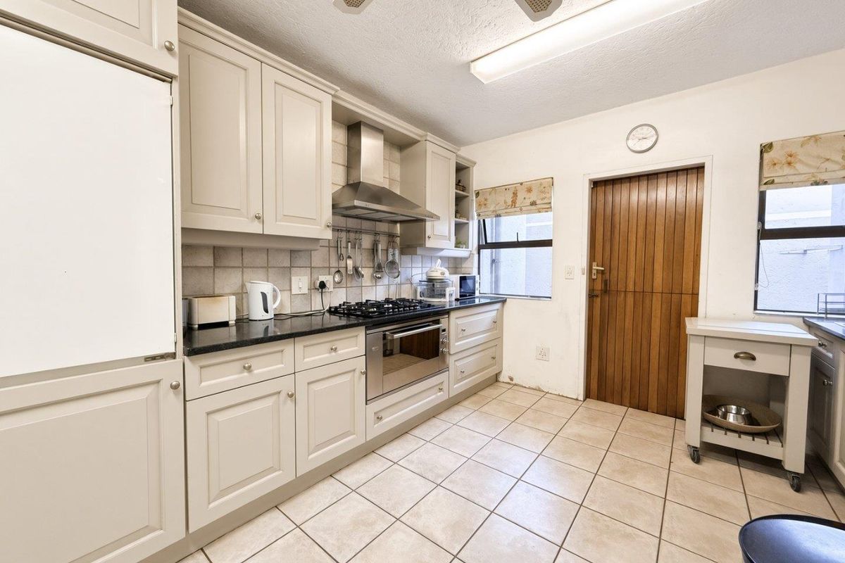 Functional kitchen featuring neutral cabinetry, granite countertops, gas hob, built-in oven, and tiled flooring with direct access to an exterior door.