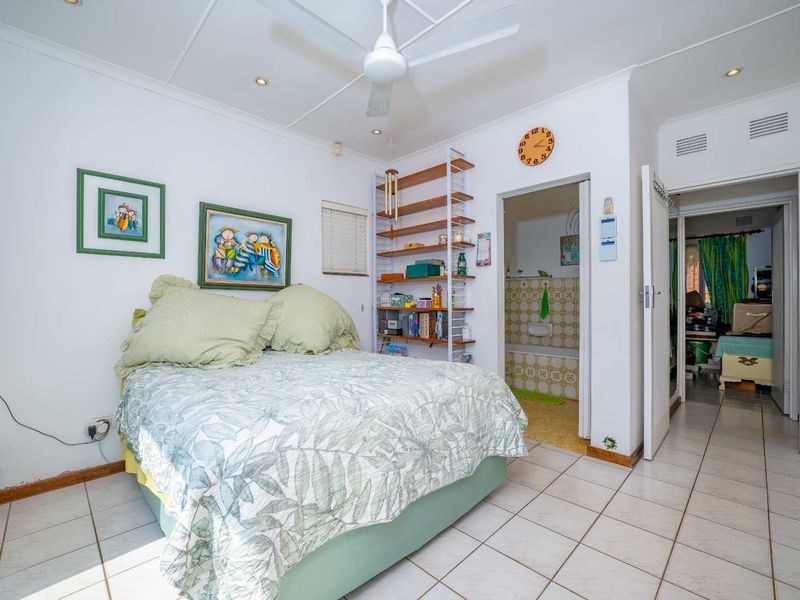 A bedroom featuring tiled flooring, a ceiling fan, and direct access to an en-suite bathroom.