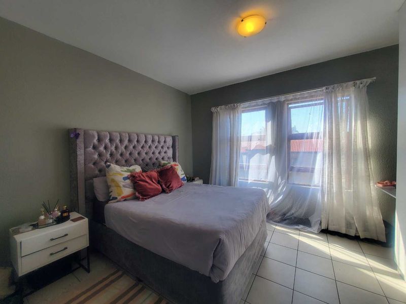 A well-lit bedroom featuring tiled flooring and a neutral wall finish, providing a comfortable and functional sleeping space.