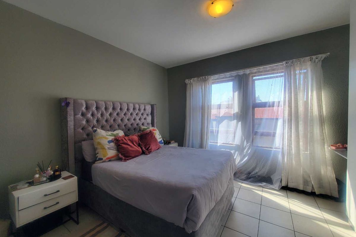 A well-lit bedroom featuring tiled flooring and a neutral wall finish, providing a comfortable and functional sleeping space.