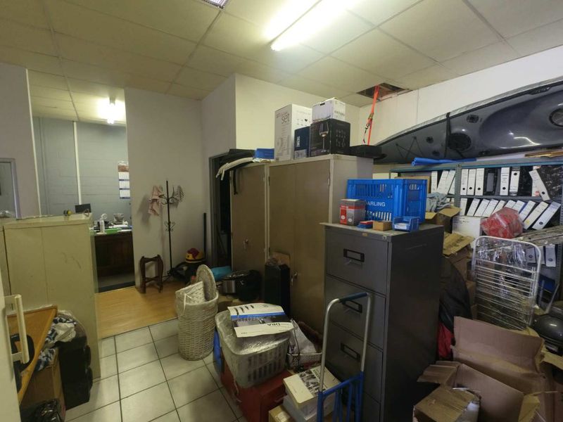 A cluttered utility or storage area featuring tiled flooring, suspended ceiling panels, and built-in metal cabinetry, currently used for general storage.