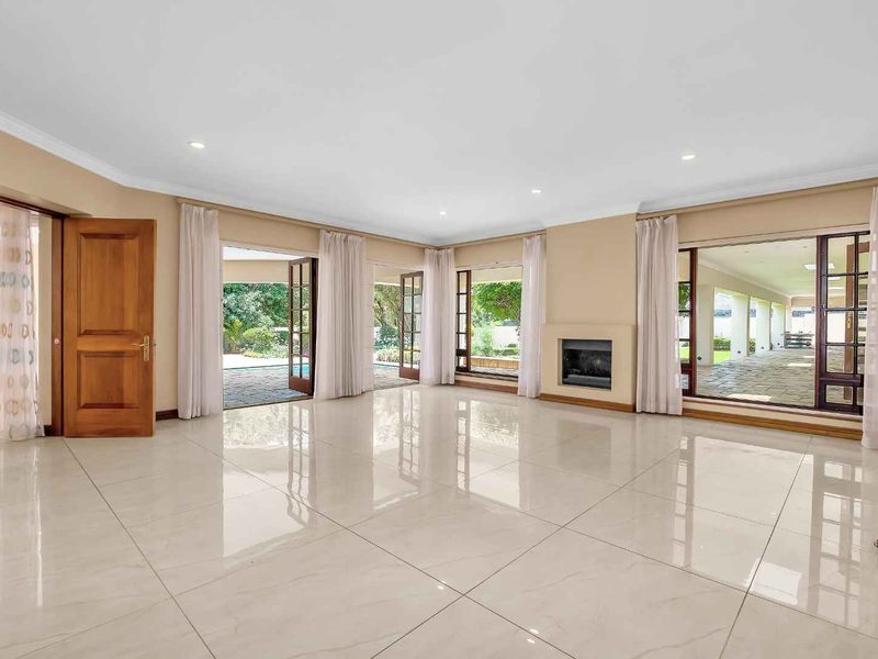 Spacious, light-filled living room featuring polished porcelain tiles, a built-in fireplace, and multiple glass doors providing seamless access to the outdoor patio area.