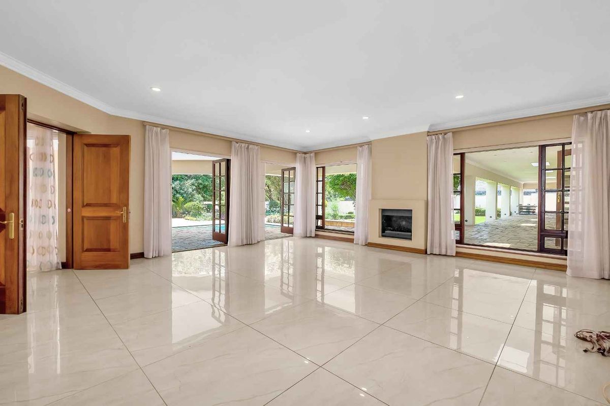 Spacious, light-filled living room featuring polished porcelain tiles, a built-in fireplace, and multiple glass doors providing seamless access to the outdoor patio area.