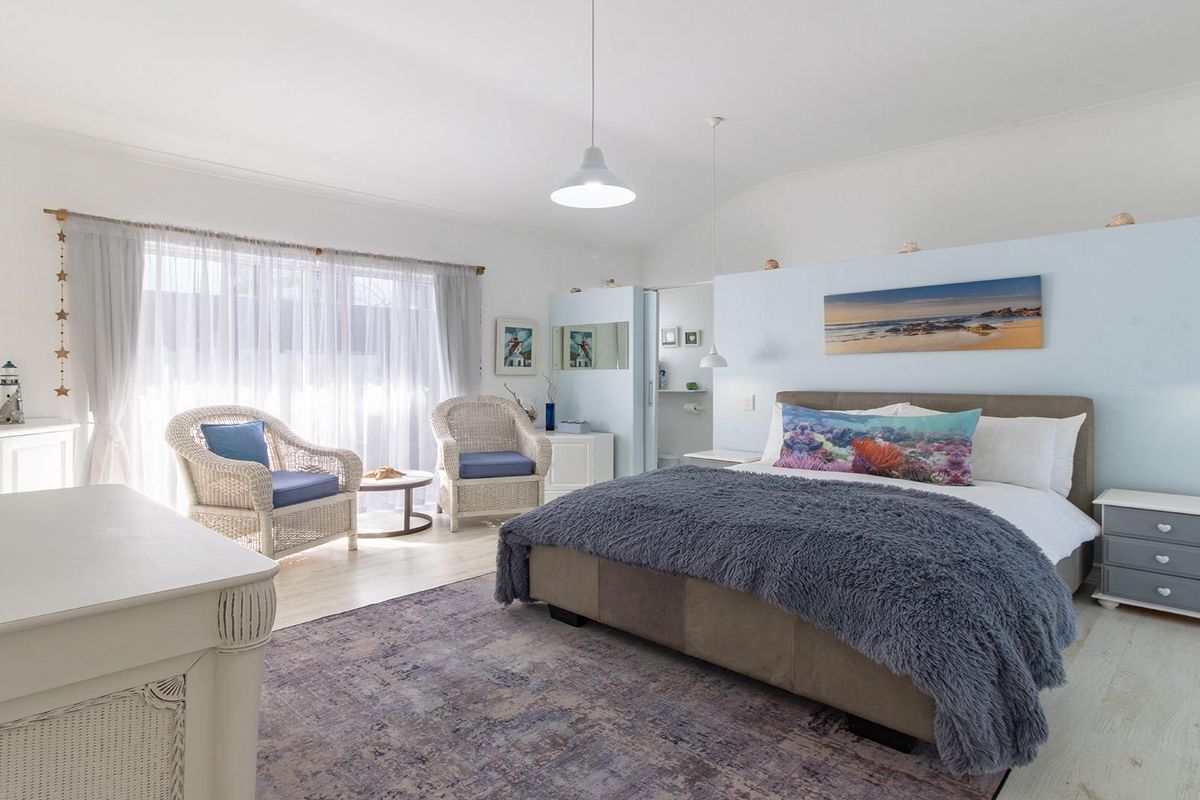 A bright and spacious bedroom featuring laminate flooring, pendant lighting, and a sliding glass door providing access to the exterior.