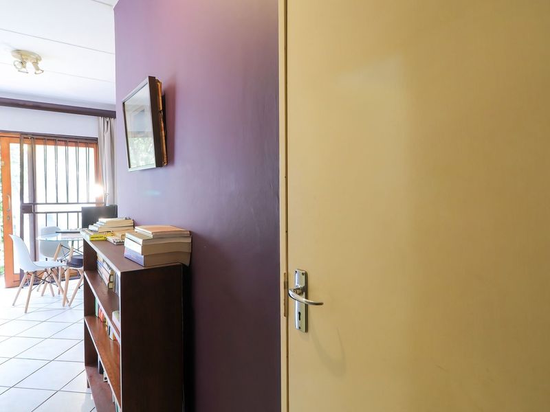 A hallway area featuring tiled flooring and a sliding glass door leading to an outdoor space, with a neutral and purple accent wall.