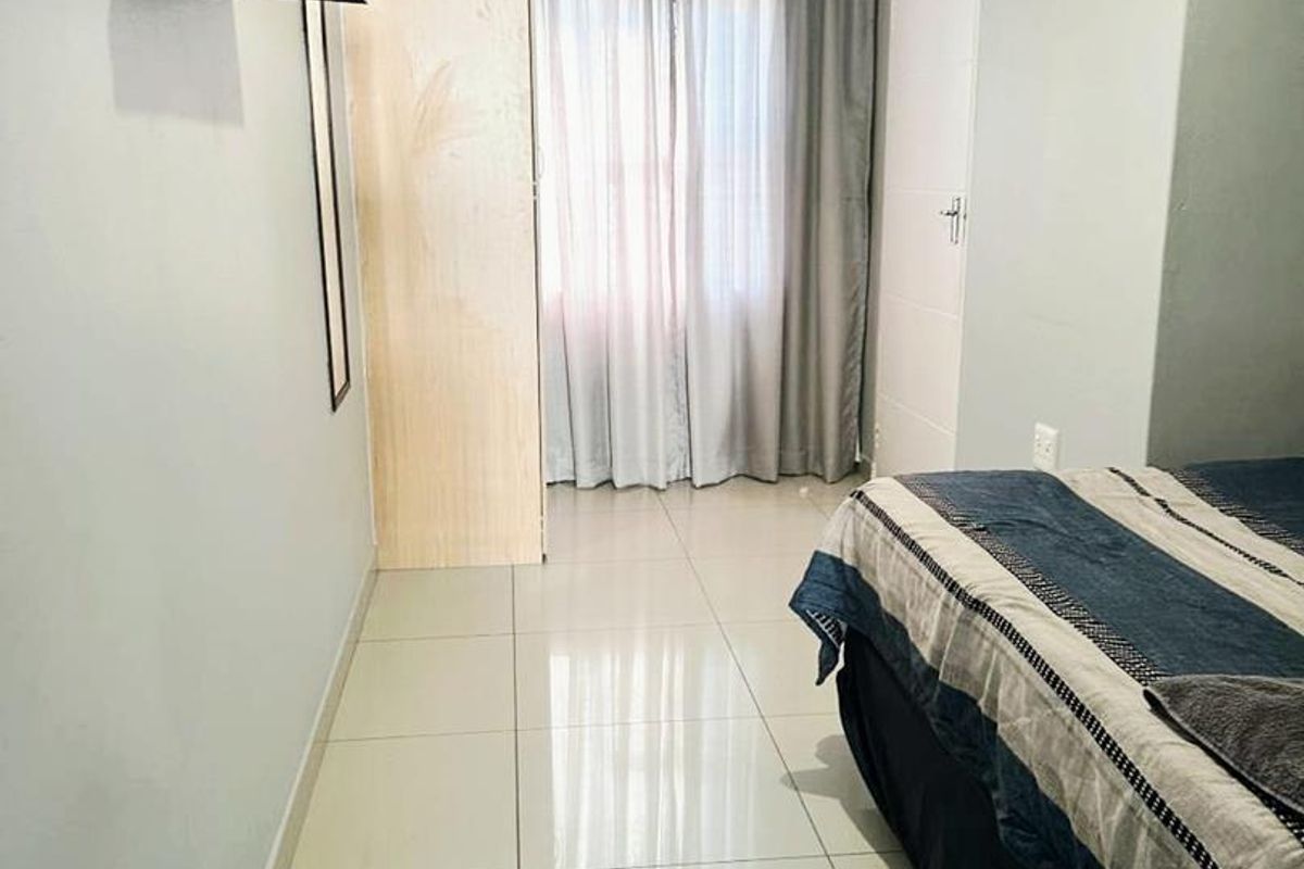 A bedroom featuring tiled flooring and a built-in wardrobe, offering a functional and neutral living space.