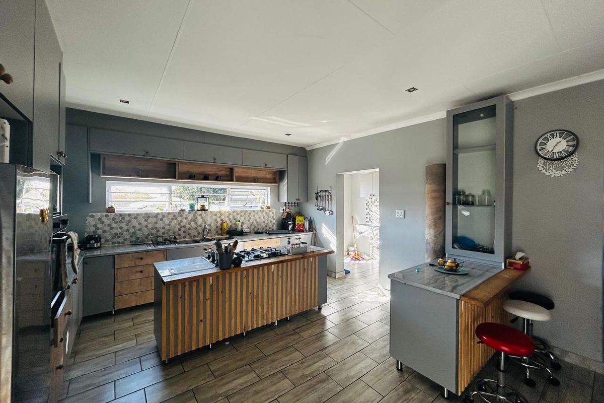 Modern kitchen featuring a central island with a gas hob, built-in oven, tiled backsplash, and ample cabinetry with a breakfast bar area.