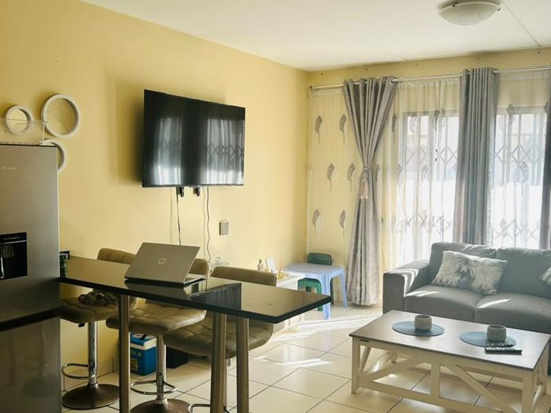 Open plan living area featuring ceramic floor tiles and a sliding glass door with security gate, providing access to the exterior.