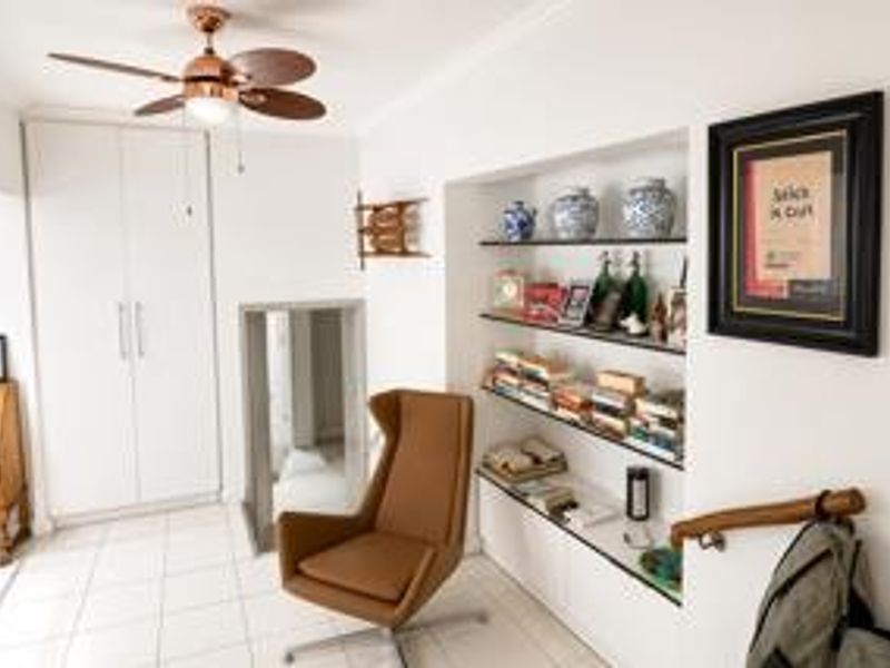 A bright living area featuring built-in storage cupboards, recessed shelving, and a ceiling fan, providing a functional and well-maintained space.