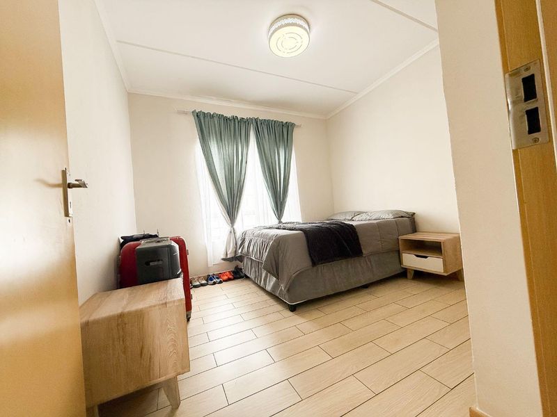 A functional bedroom featuring light-toned tiled flooring and a central ceiling light fixture, providing a clean and neutral space.
