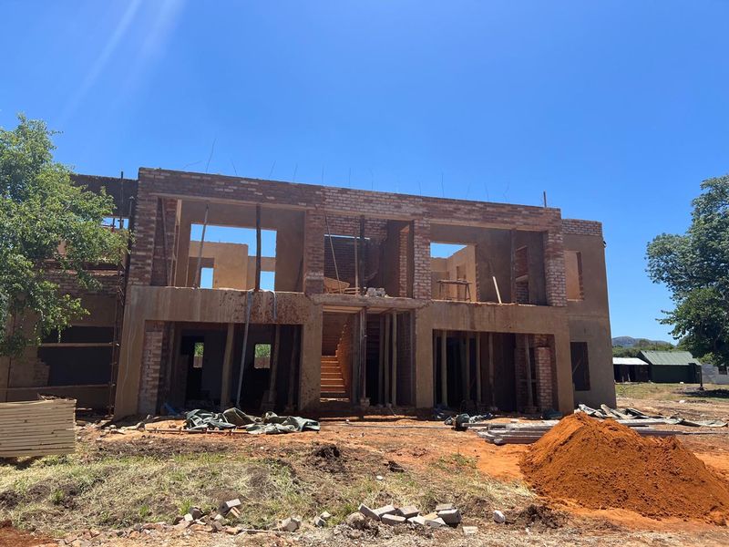 A two-story residential property currently under construction, featuring exposed brickwork and an open structural frame awaiting completion.