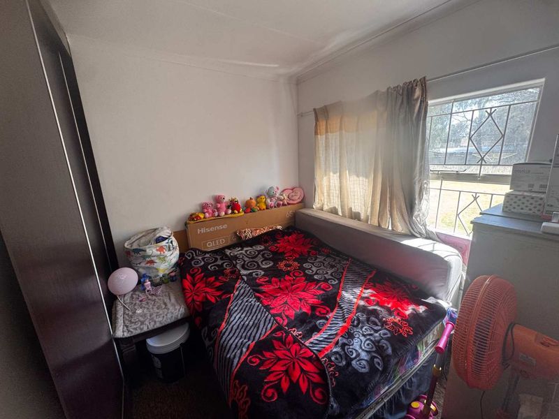 A bedroom featuring a built-in wardrobe and a window fitted with security bars, providing natural light and functional storage space.