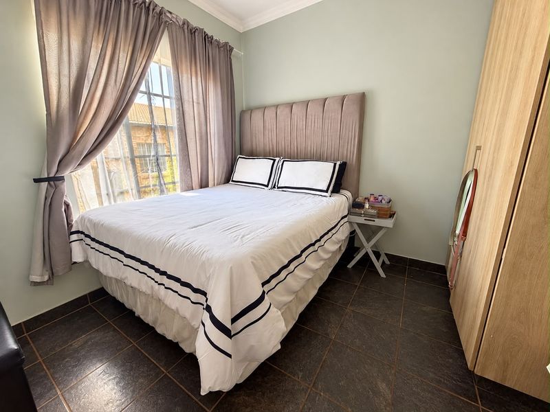 A cozy bedroom featuring tiled flooring, a built-in wardrobe, and a window with natural light.