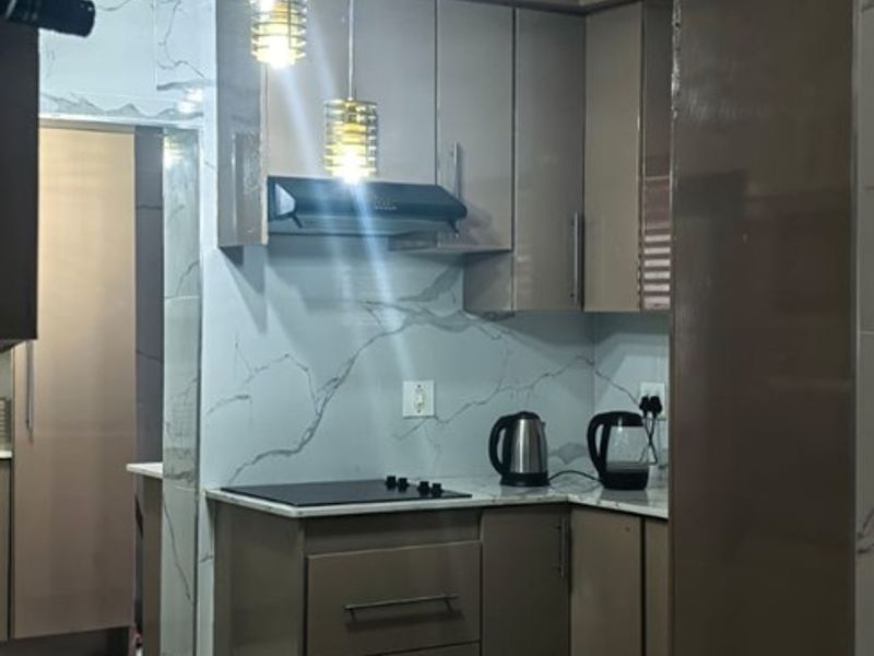 A modern kitchen featuring sleek cabinetry, marble-look countertops and backsplash, an integrated electric hob, and stylish pendant lighting.