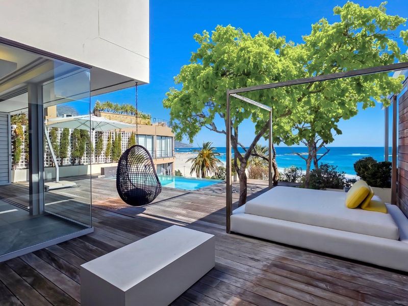 A luxurious outdoor patio featuring timber decking, a private swimming pool, and stunning ocean views, seamlessly connected to the interior living space.