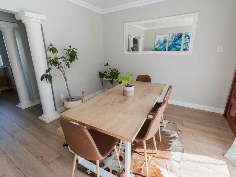 A bright dining room featuring light laminate flooring, decorative columns, and crown molding, creating an open and inviting atmosphere.