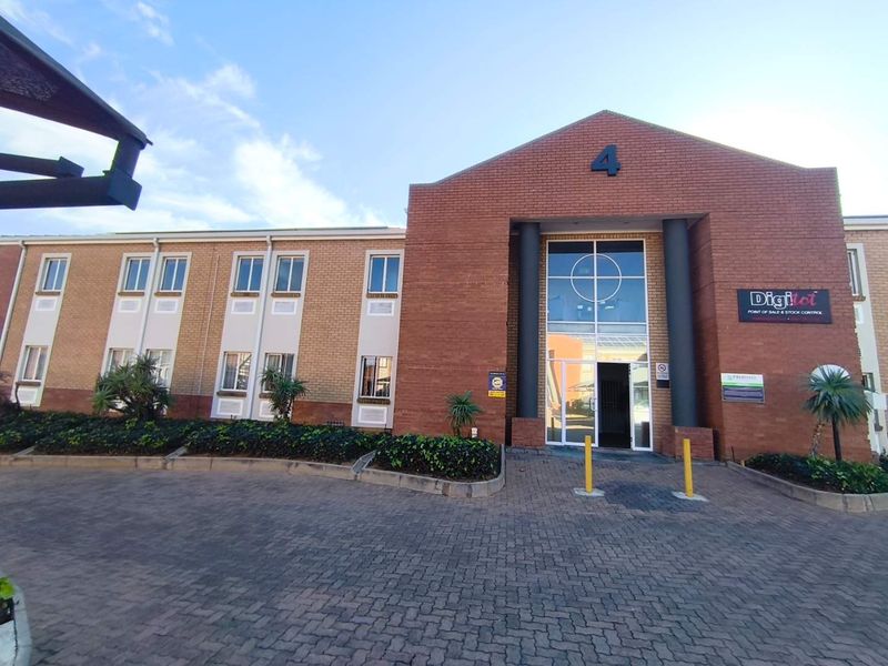 Front elevation of a professional office building featuring a brick facade, paved driveway, and a prominent glass entrance.