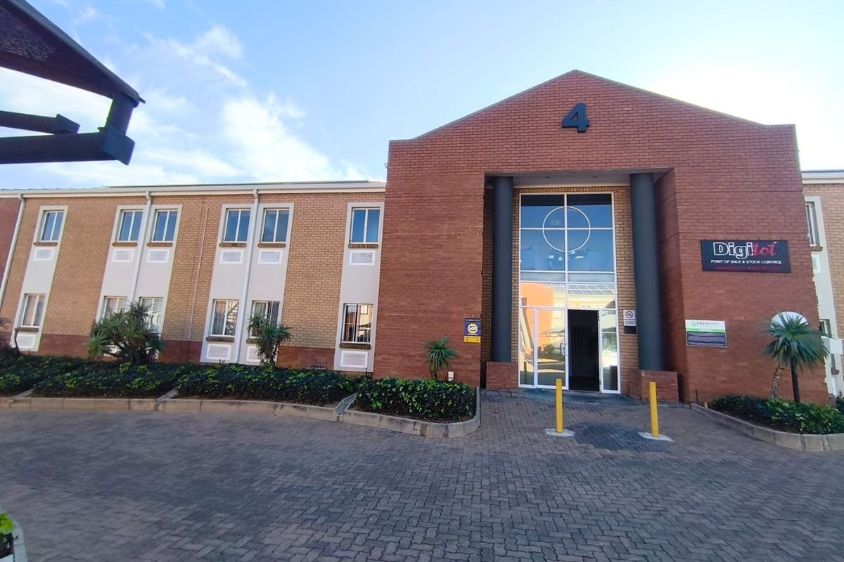 Front elevation of a professional office building featuring a brick facade, paved driveway, and a prominent glass entrance.