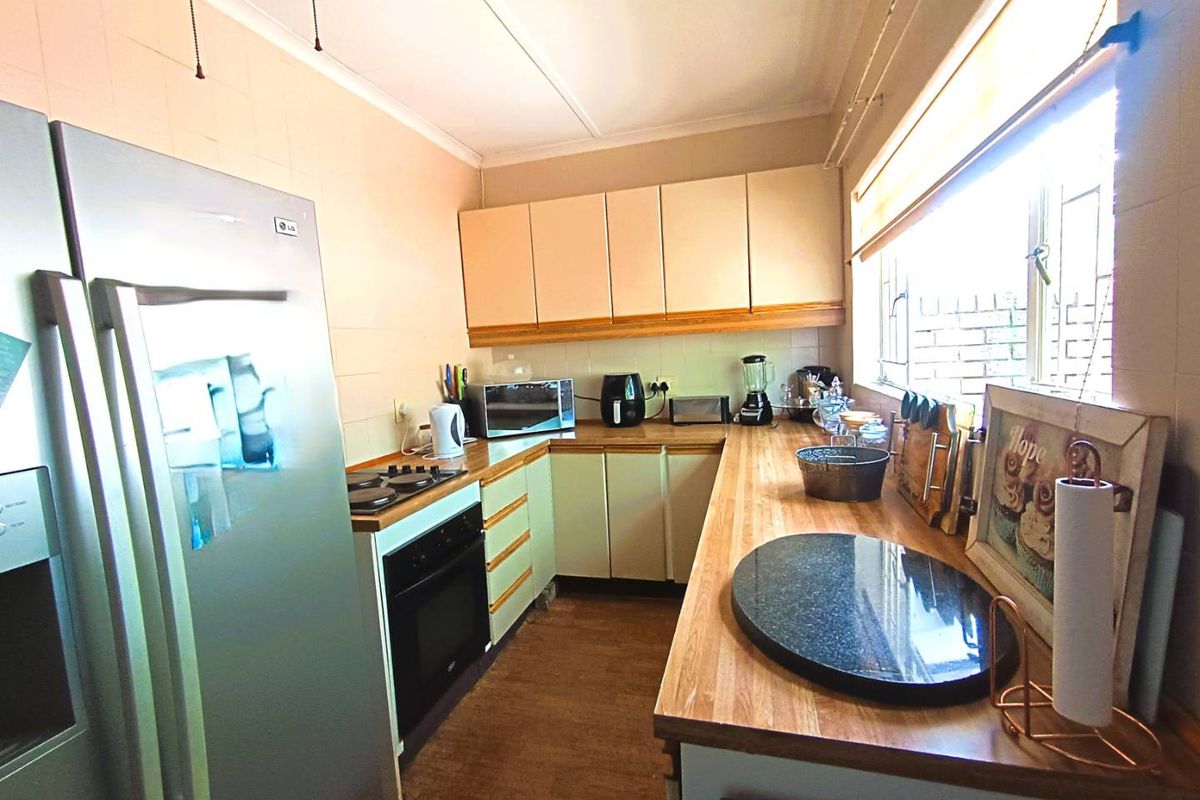 A functional kitchen featuring wooden countertops, built-in cabinetry, an integrated oven, and a gas hob, illuminated by natural light from a large side window.