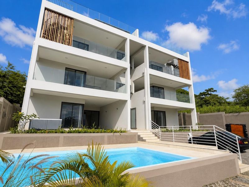 Modern multi-story apartment building featuring glass-railed balconies, a private swimming pool, and contemporary architectural design.