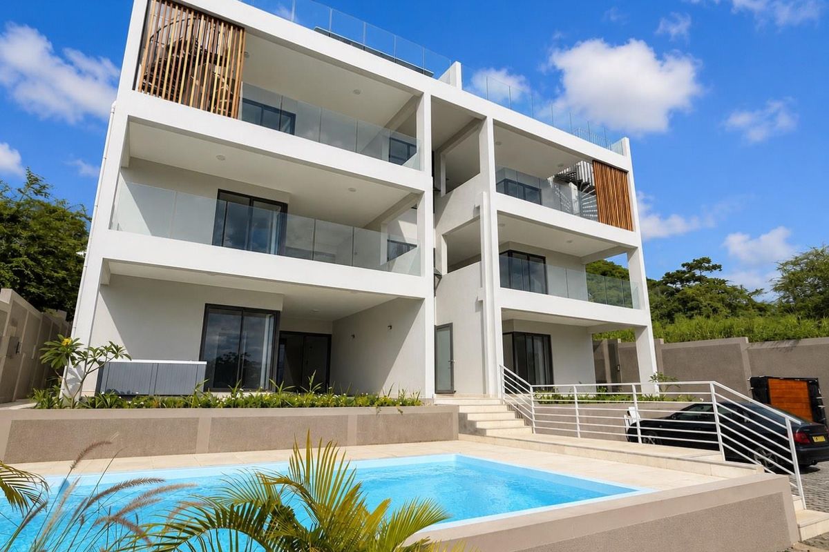 Modern multi-story apartment building featuring glass-railed balconies, a private swimming pool, and contemporary architectural design.