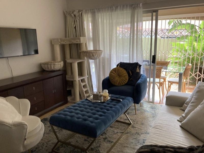 A comfortable living room featuring a sliding glass door with security gate, providing access to an outdoor patio area.