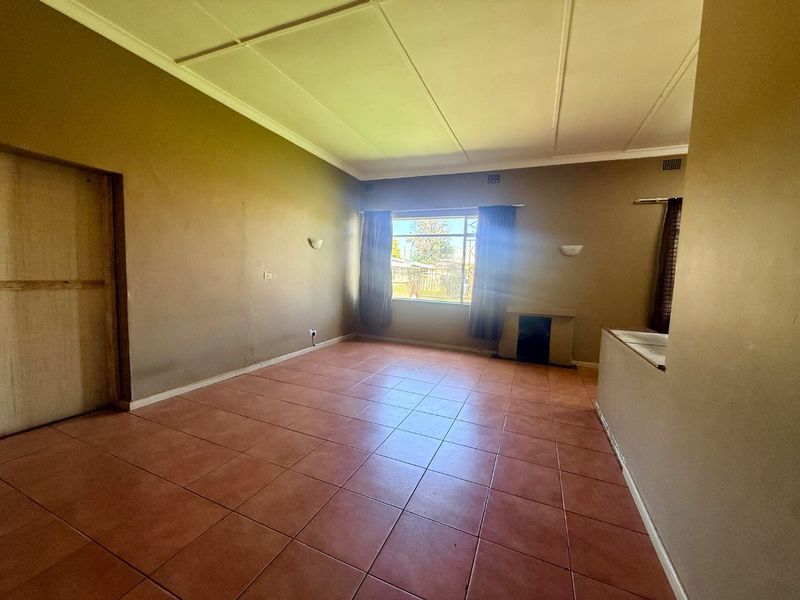 An empty living room featuring tiled flooring, a built-in fireplace, and wall sconces, offering a blank canvas for potential renovation and interior design updates.