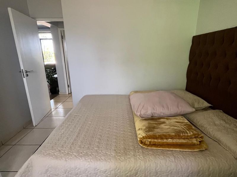 A bedroom featuring tiled flooring and a neutral interior, providing a functional space with direct access to the hallway.