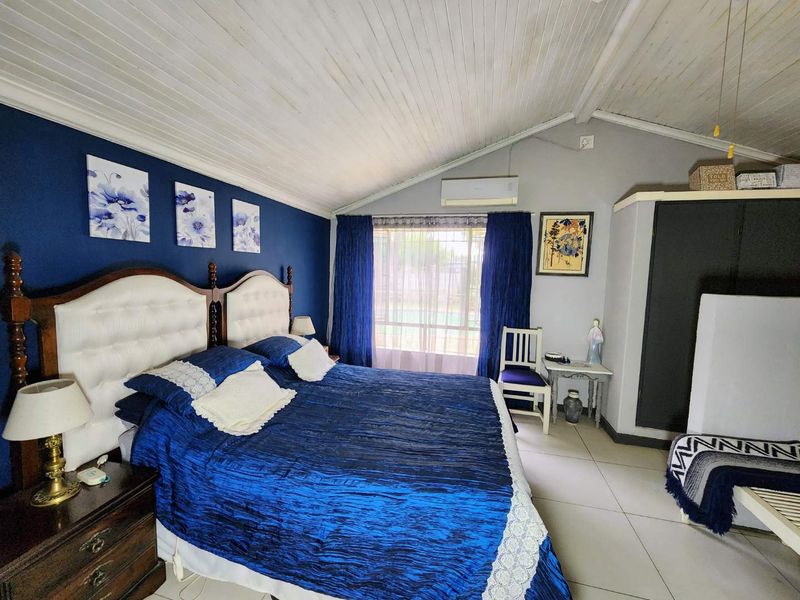 Spacious bedroom featuring a vaulted timber ceiling, tiled flooring, and a built-in wardrobe, complemented by a split-system air conditioner for climate control.