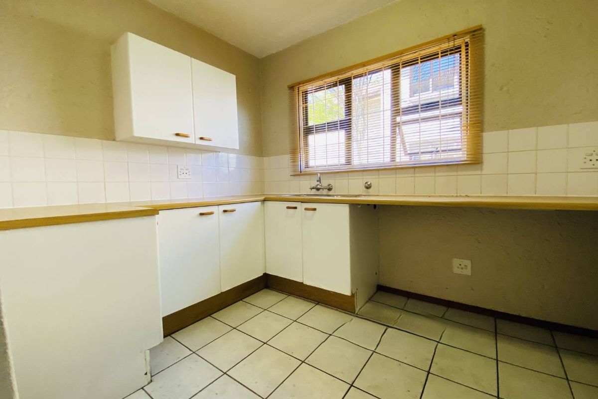 A functional kitchen featuring white cabinetry, laminate countertops, tiled backsplash, and ceramic flooring, offering a blank canvas for potential modern updates.