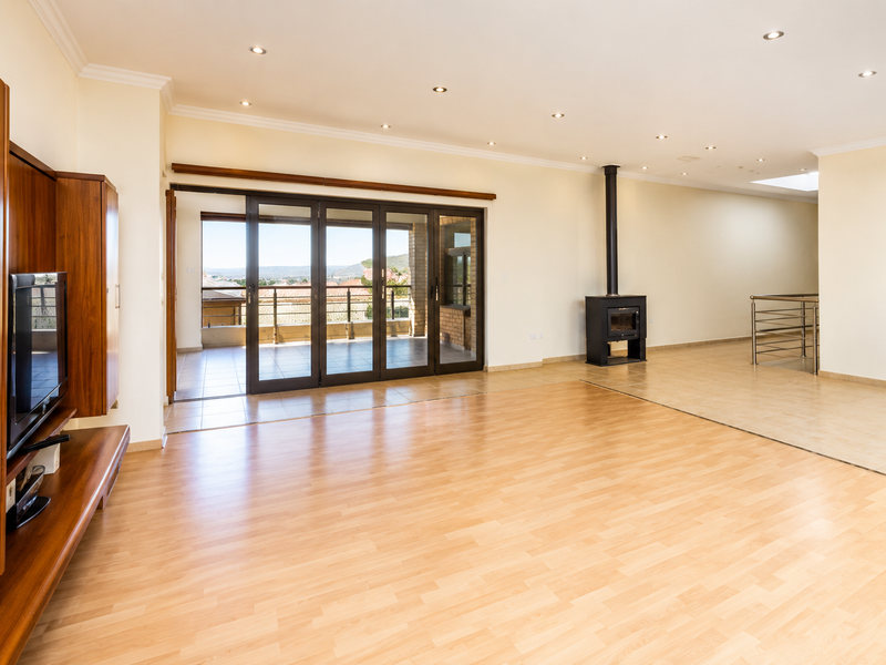 Spacious living area featuring laminate and tiled flooring, a built-in wood-burning fireplace, and large sliding doors opening to an outdoor balcony.