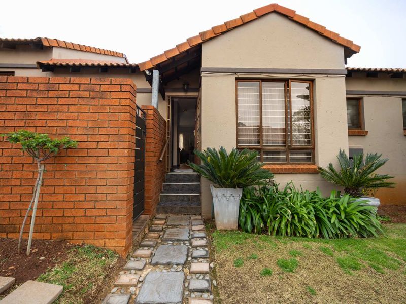 Front entrance of the cluster home featuring a stone walkway, brick boundary wall, and terracotta tiled roof.