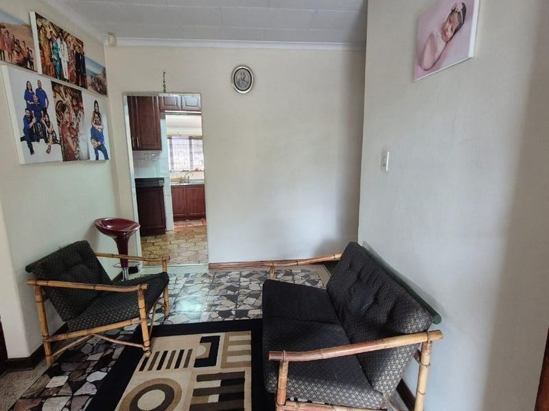A living area featuring tiled flooring with a direct view into the adjacent kitchen space.