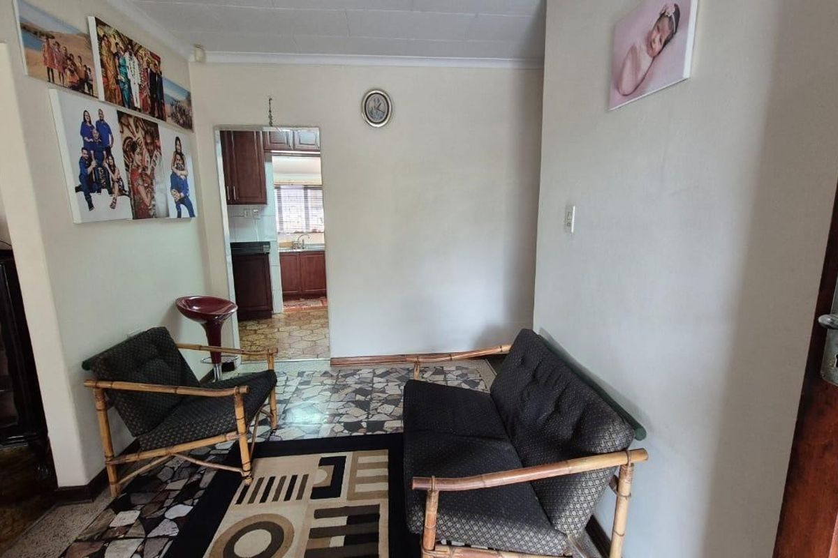 A living area featuring tiled flooring with a direct view into the adjacent kitchen space.