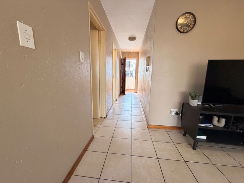 A functional hallway featuring tiled flooring and neutral wall tones, providing access to multiple rooms within the apartment.