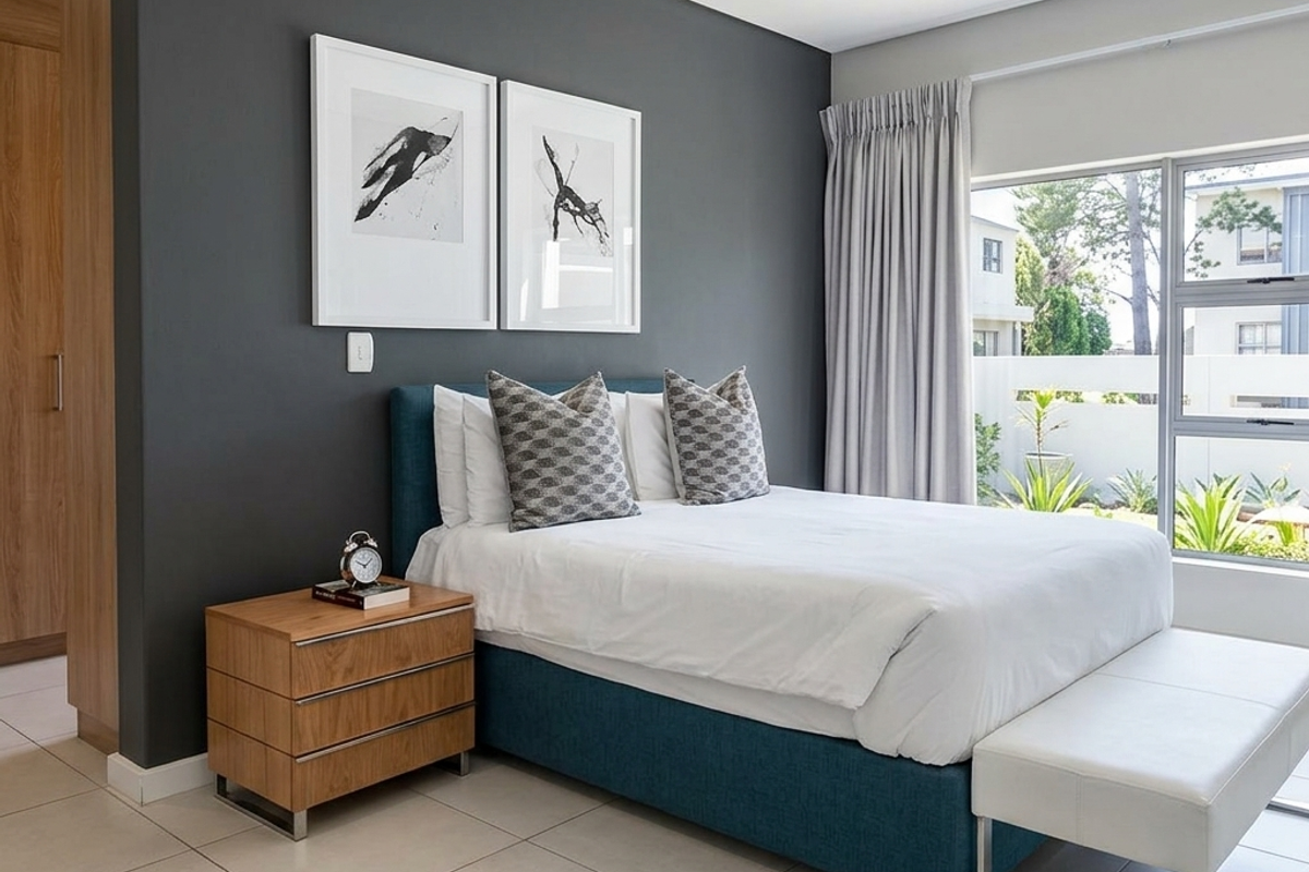 Modern bedroom featuring neutral tiled flooring, a dark accent wall, built-in cabinetry, and large windows providing natural light.