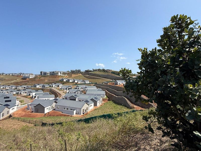 An elevated view of a residential estate development featuring multiple modern homes, paved roads, and engineered retaining walls.