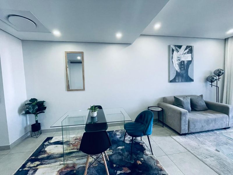 Modern open-plan living and dining area featuring neutral tiled flooring and recessed ceiling lighting, creating a bright and contemporary atmosphere.