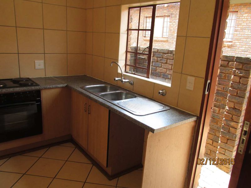 A functional kitchen featuring built-in cabinetry, laminate countertops, a double bowl stainless steel sink, and a built-in oven with hob.