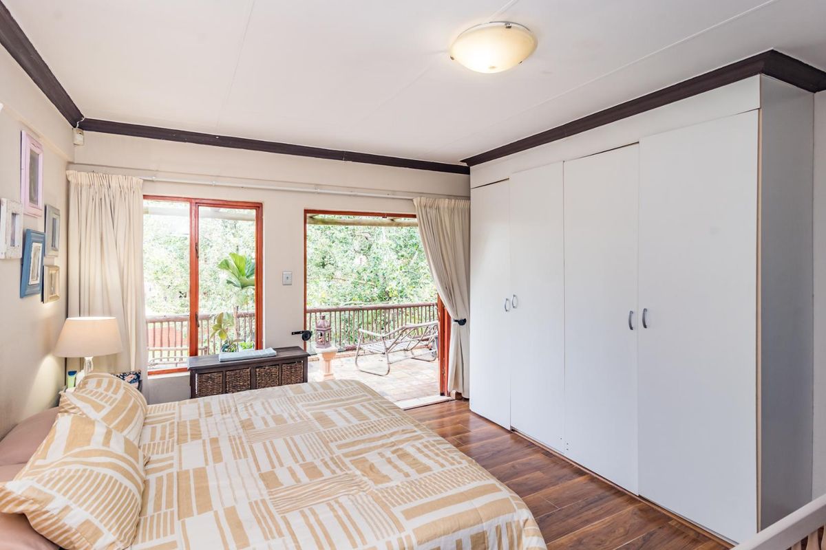 Bedroom featuring built-in wardrobes, timber flooring, and direct access to a private balcony through sliding glass doors.
